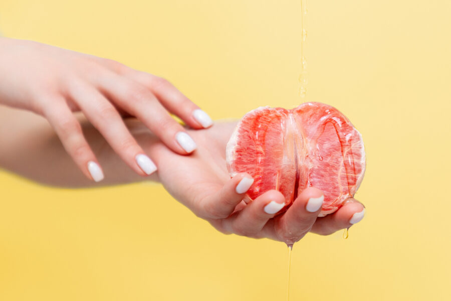 Mão segurando uma laranja, em referência a saúde íntima no climatério.