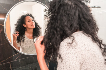Mulher na menopausa em frente ao espelho cuidando da pele e cabelo.